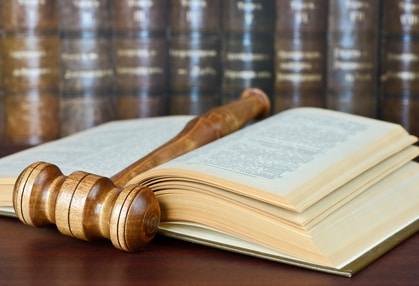 Wood gavel and old yellowed book on the background of shelves of old books